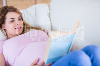 Pregnant woman reading a book on couch