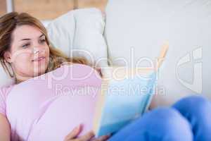 Pregnant woman reading a book on couch