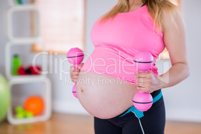 A pregnant woman holding dumbbells