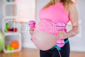 A pregnant woman holding dumbbells
