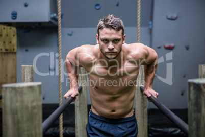 Portrait of muscular man exercising on parallel bars