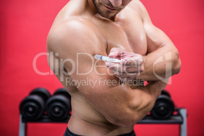Muscular man injecting steroids