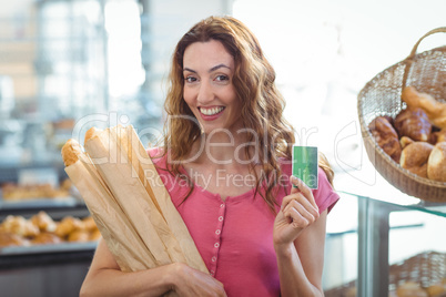 Pretty brunette holding credit card and baguettes
