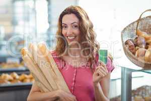 Pretty brunette holding credit card and baguettes