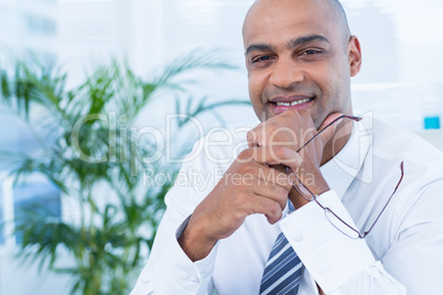 Smiling businessman holding reading glasses