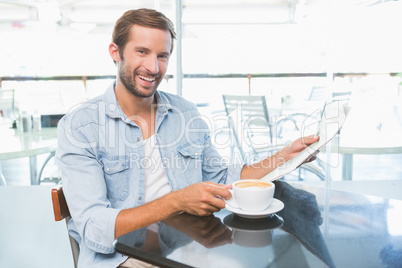 Young happy man holding the newspapers while looking at the came
