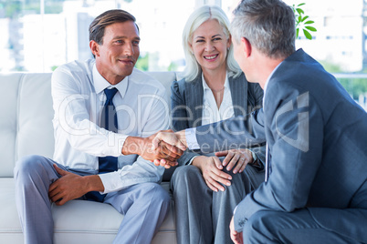 Business people shake hands on couch