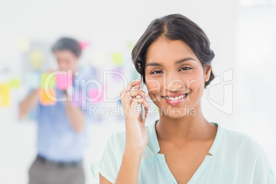 Businesswoman having phone call while her colleague posing