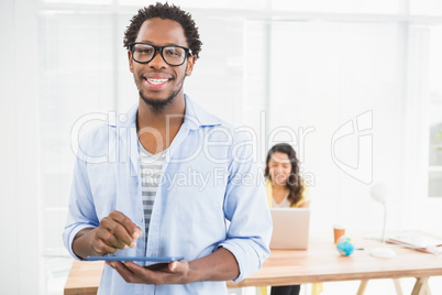 Smiling man posing in front of his colleague with tablet compute