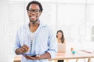 Smiling man posing in front of his colleague with tablet compute