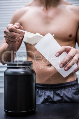 Muscular man making protein cocktail