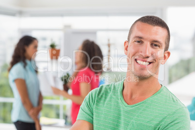 Casual male artist with colleagues in background at office