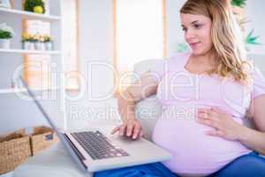 Happy pregnant woman using her laptop