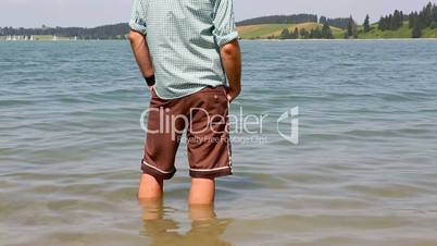 Bavarian cools his feet in a lake