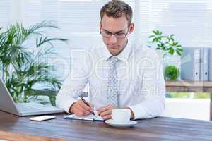 Concentrated businessman writing on a notebook