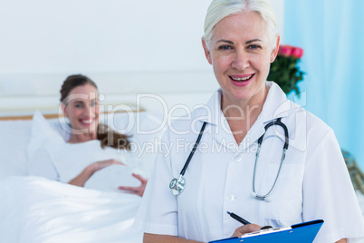 Female doctor and pregnant woman smiling at camera