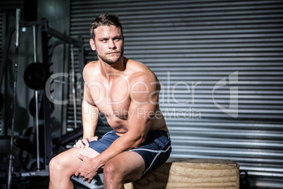 Focused muscular man sitting on a box