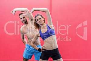 Muscular couple doing arms stretching