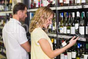 Smiling pretty woman looking at wine bottle