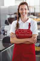 Pretty barista smiling at camera with arms crossed