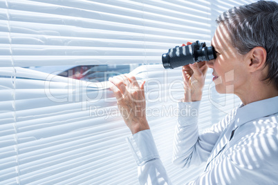 Businesswoman looking through binoculars in the office