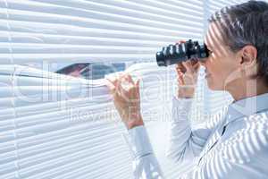 Businesswoman looking through binoculars in the office