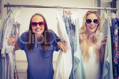 Happy friends looking through the clothes rack