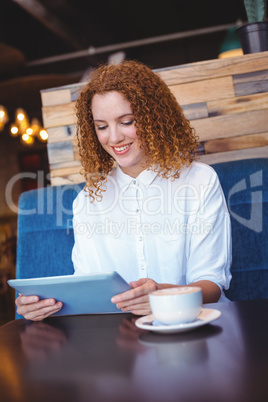 Pretty girl using a small tablet at table