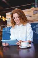Pretty girl using a small tablet at table
