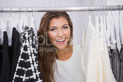 Portrait of smiling woman standing in-between clothes