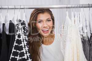Portrait of smiling woman standing in-between clothes
