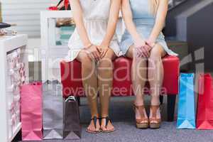 Close up of two women sitting with shopping bags