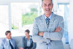 Businessman looking at camera with his colleagues behind him