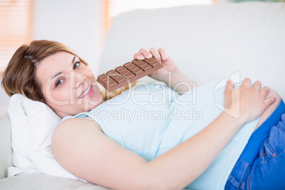 Pregnant woman looking at camera and eating chocolate
