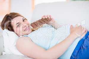 Pregnant woman looking at camera and eating chocolate