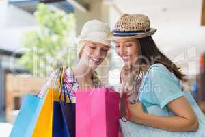 Two happy women looking at shopping bags