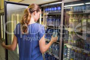 Pretty woman taking bottle of water in fridge