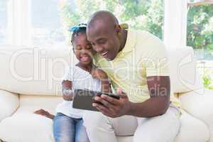 Happy smiling father using digital tablet with her daughter on c