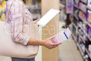 Pretty blonde woman looking at a product and using her digital t