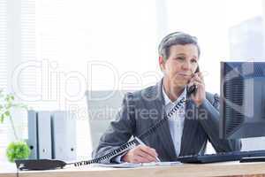 Smiling businesswoman phoning and writing