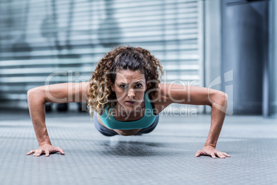 Attentive muscular woman doing pushups