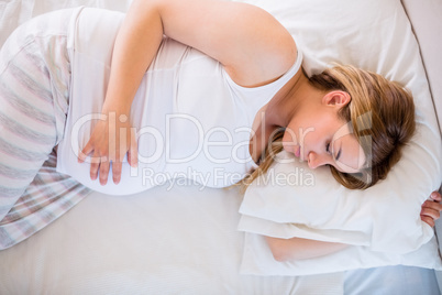 Pregnant woman sleeping on bed