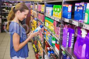 Thoughtful pretty brunette looking at product in shelf