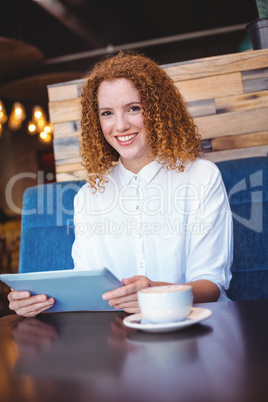 Pretty girl using a small tablet at table