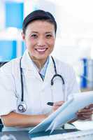 Happy doctor writing on a clipboard and smiling at camera