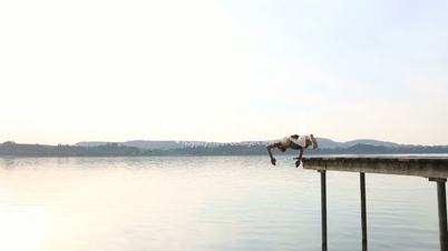 Young man jumps off the dock into water
