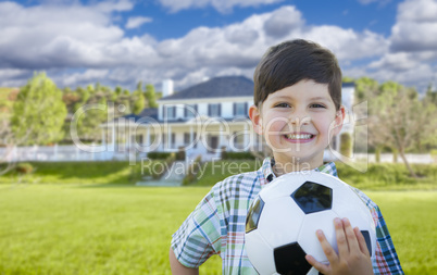 Smiling Young Boy Holding Soccer Ball In Front of House