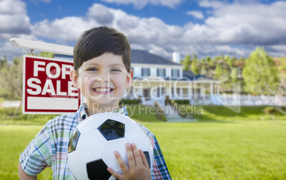 Boy Holding Ball In Front of House and Sale Sign