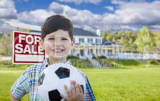 Boy Holding Ball In Front of House and Sale Sign