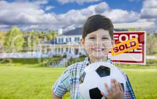 Boy Holding Ball In Front of House and Sold Sign